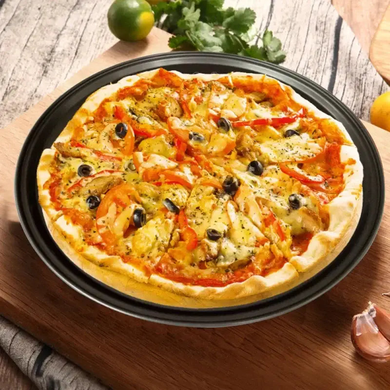A freshly baked pizza on a non stick black carbon steel perforated pizza pan baking tray by decorbites