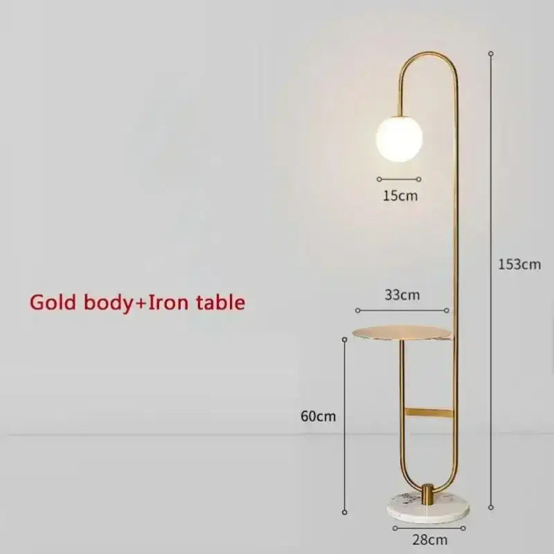 Gold finished floor lamp with curved metallic frame, spherical white bulb, and marble base for living room use