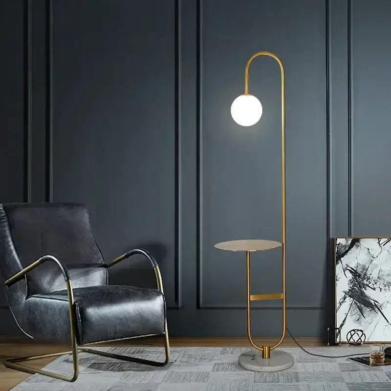 Gold-toned floor lamp with curved minimalist design and white glass shade beside a black metal led floor table