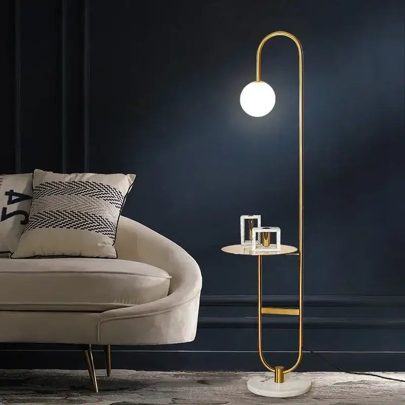 Gold-toned floor lamp with curved minimalist design and spherical glass bulb beside nordic black metal led floor table lamp