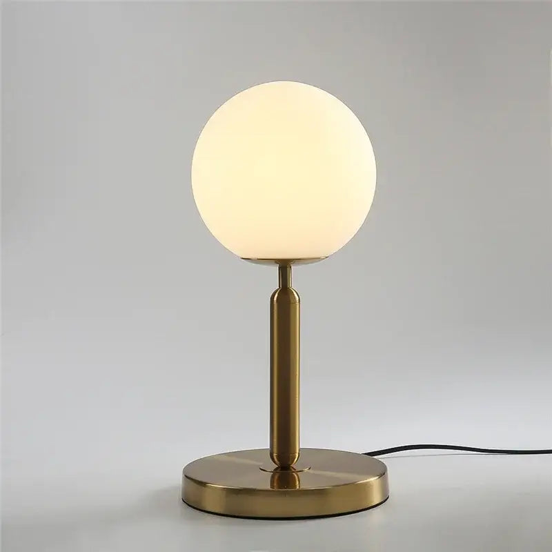 A sleek brass-finished Nordic table lamp with a frosted glass ball LED shade for bedroom decorbites glass ball decor
