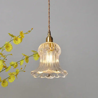 Clear glass pendant light fixture with fluted bell-shaped design and brass metal for kitchen lighting