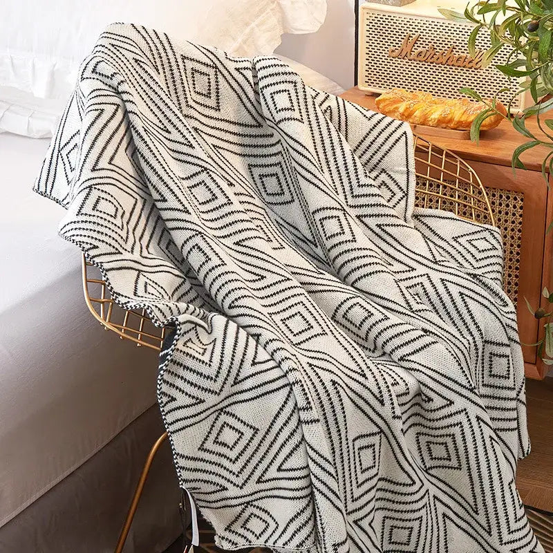 A cozy cream and black decorbites grey knitted woolen blanket with bold geometric patterns for living room decor