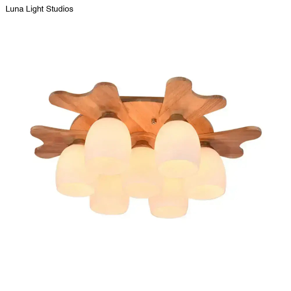 Warm-toned wooden ceiling light fixture featuring five cream glass bell shades in a symmetrical leaf pattern for bedroom use