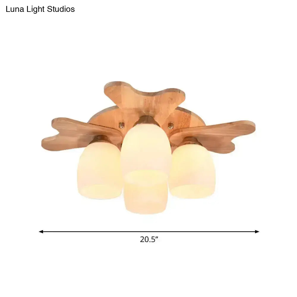 Wooden ceiling light fixture with three cream glass bell shades and leaf-shaped wooden arms for bedroom use