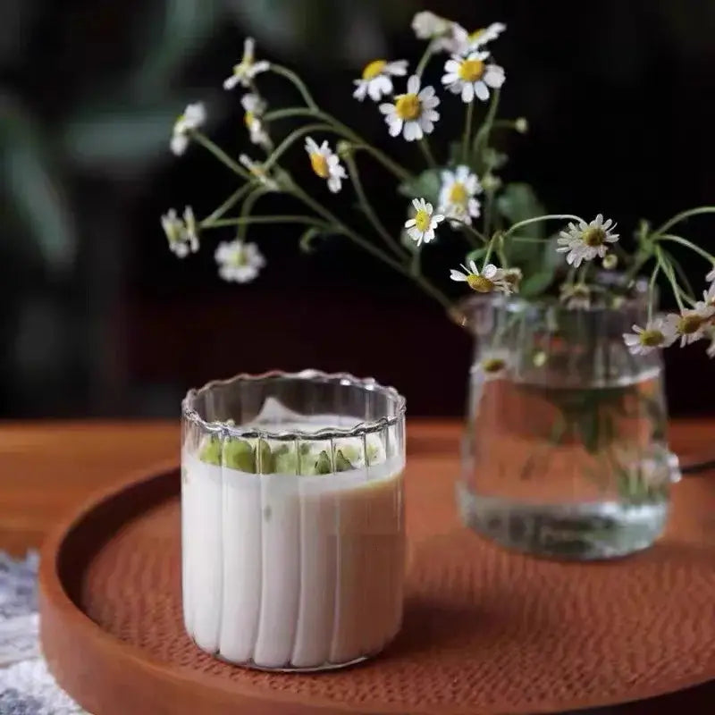 A clear creamy white beverage in a nordic glass ripple cup with gold leaf spoon in dining room setting