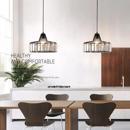 Two black-framed nordic led crystal pendant lamps with clear glass accents hang above a dining table chandelier