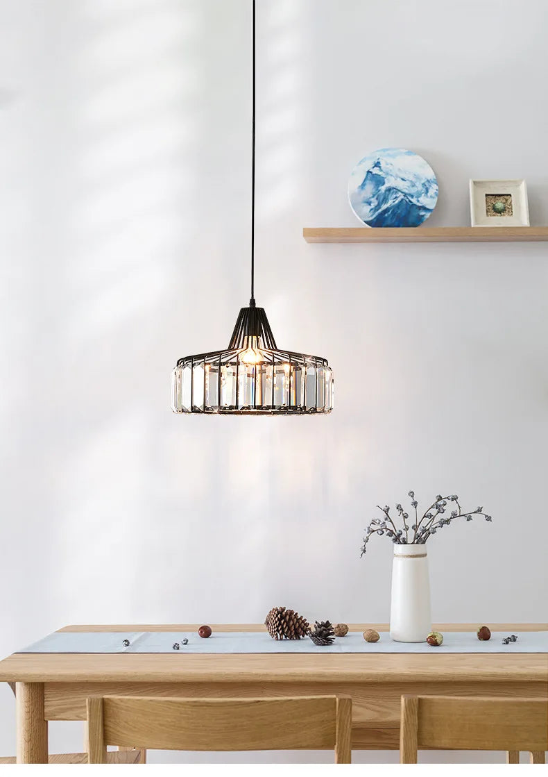 A nordic led crystal pendant lamp with black iron frame and clear glass panels hanging above a wooden dining table