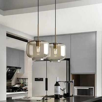 Two nordic led glass pendant lights with smoked glass shades and brass accents hang above a dining room island