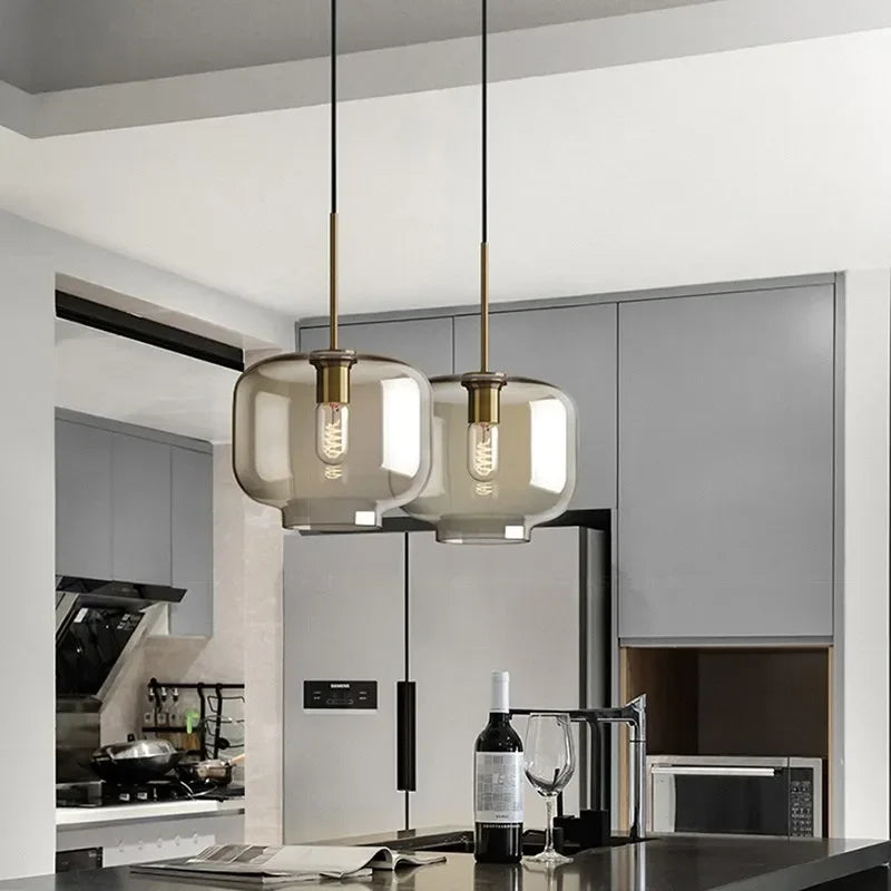 Two nordic led glass pendant lights with smoked glass shades and brass accents hang above a dining room island