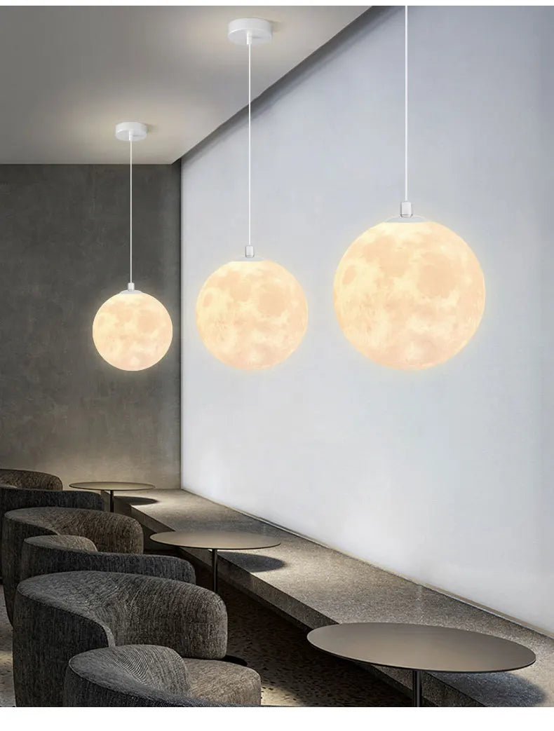Three warm glowing moon-like nordic led pendant chandeliers hanging in dining room kitchen for ambient lighting