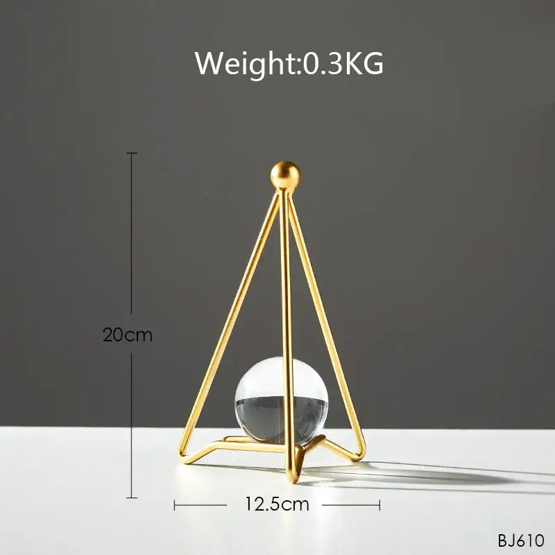 Gold-toned triangular metal stand holding a clear glass sphere with dark liquid for nordic light luxury crystal ball crafts
