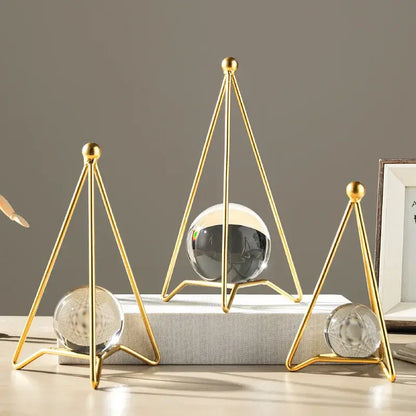 Gold-toned triangular metal stands holding clear and dark crystal ball crafts for nordic light luxury decor