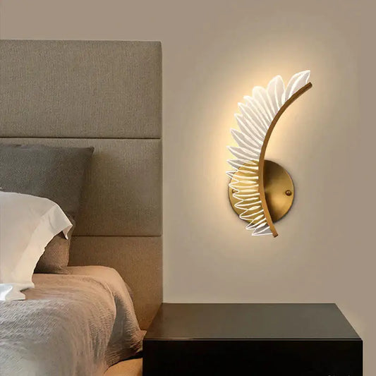 Gold-toned nordic modern art wall lamp with curved feather design and translucent white accents for bedside use