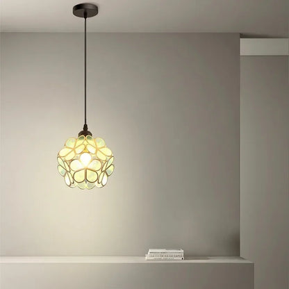 A nordic modern petal acrylic pendant lamp with greenish-yellow glass floral design and warm glow, suspended by dark chain