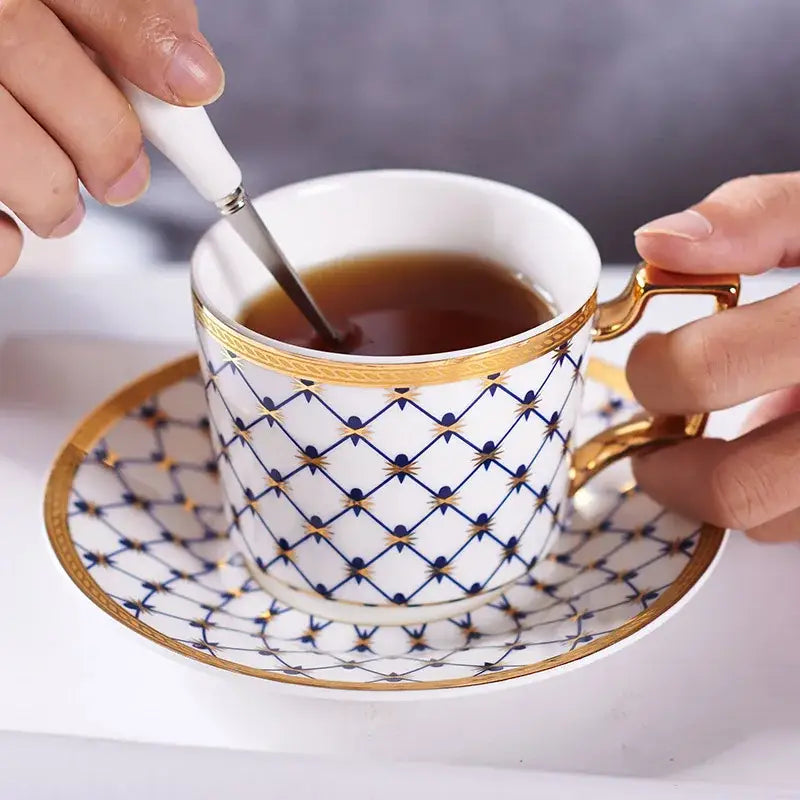 White porcelain bone china coffee cup and saucer set with navy geometric patterns and gold trim and handle