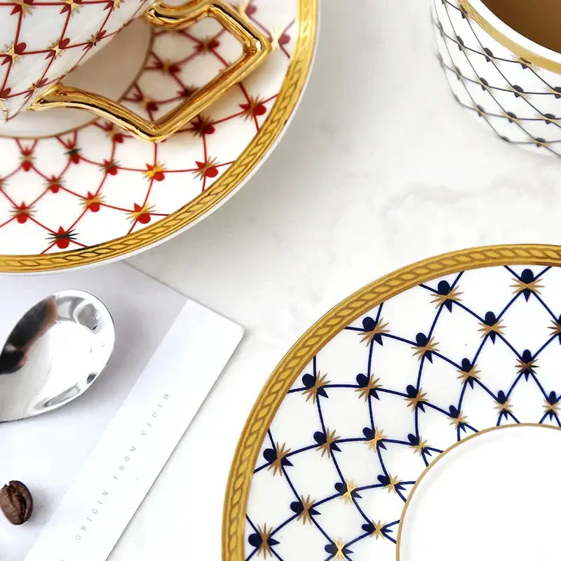White porcelain bone china coffee cup with gold handle and red starburst on matching saucer from nordic navy gold set