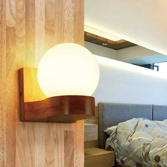 Warm-toned spherical opal glass wall sconce with polished wooden base for bedroom wall light