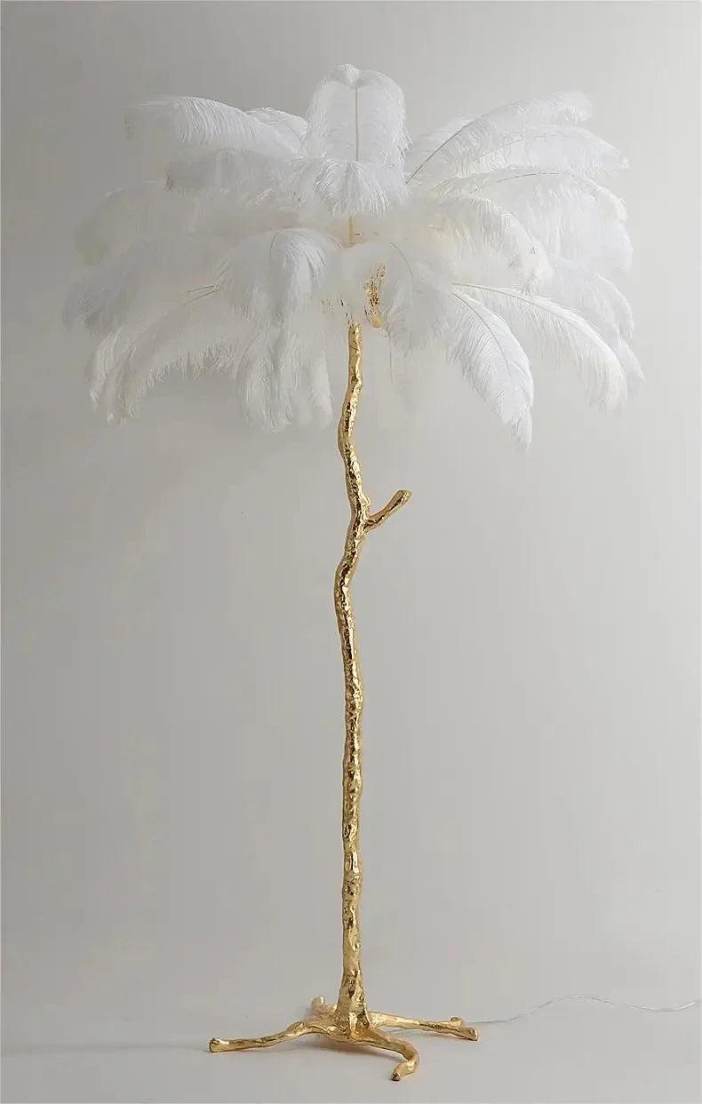 A tall elegant feather floor lamp with a golden branch-like base and white ostrich feathers for living room decor