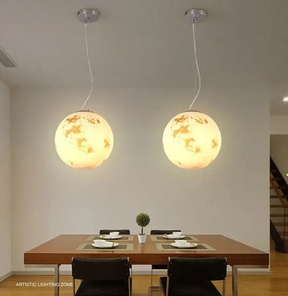 Two warm glowing nordic retro ball moon chandelier pendant lights with detailed crater surface for dining room use