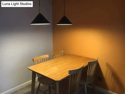 Black conical nordic simple kitchen pendant light with sleek metal fixtures hanging above a wooden dining table