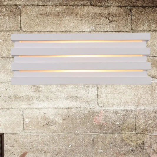 Modern white nordic style louvered wall sconce with warm light glowing through horizontal slats for bedroom use
