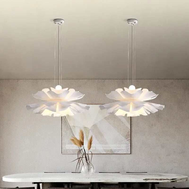 Two elegant white acrylic flower pendant chandeliers hang with layered design on slender metallic chains for bedroom decor