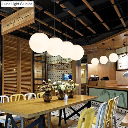 Modern nordic white glass ball pendant lights with spherical design hang in a row for living room or restaurant use