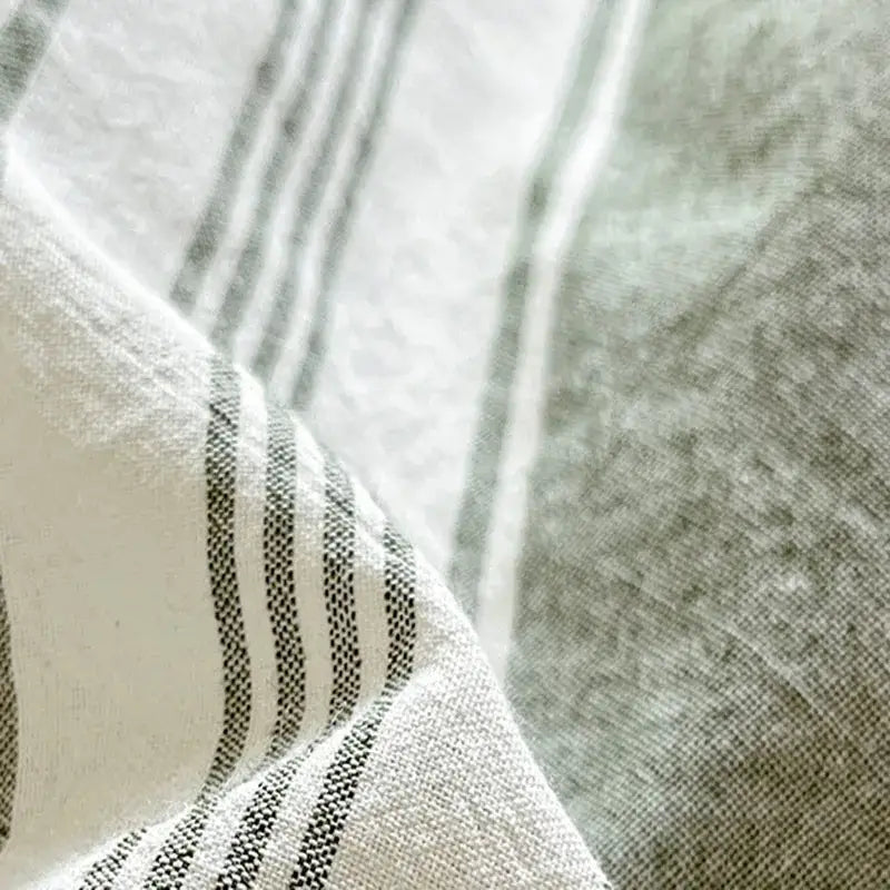 A soft textured linen fabric with subtle black and white stripes in the olive green and cream decorbites cozy striped bedding set