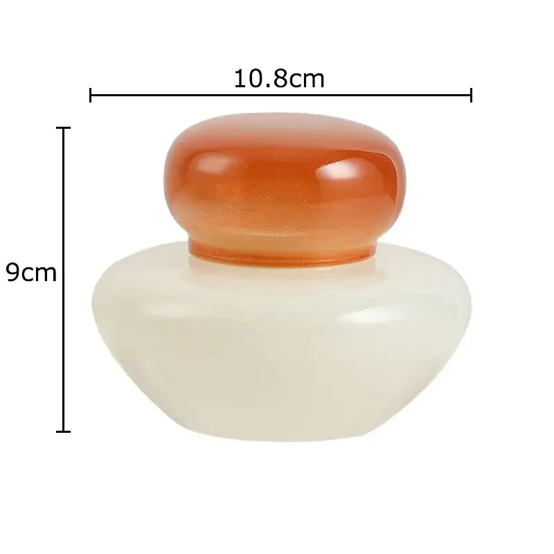 Cream-colored smooth ceramic glass storage jar with translucent amber glass lid from orange and blue glass storage set