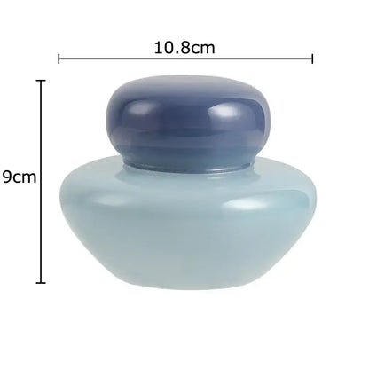 A sleek translucent light blue ceramic storage jar with a matching dark blue lid for kitchen glass storage