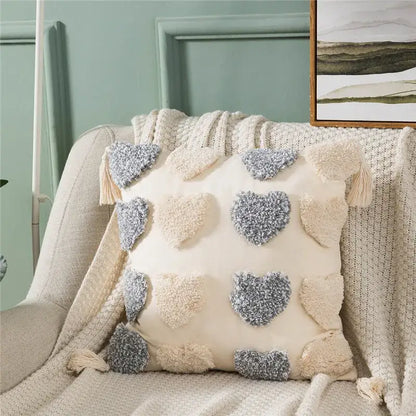Cream-colored cushion cover featuring decorbites heart embroidery with orange and grey textured appliqués and tassels