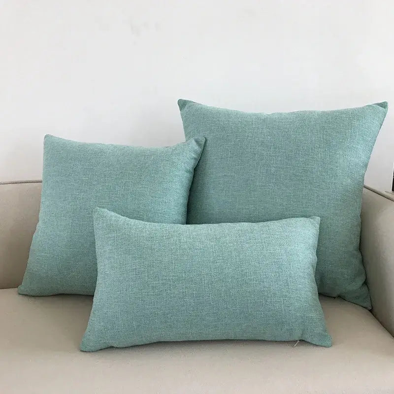 Three teal textured fabric pillows arranged on a beige couch complement decorbites ivory sofa cushion cover
