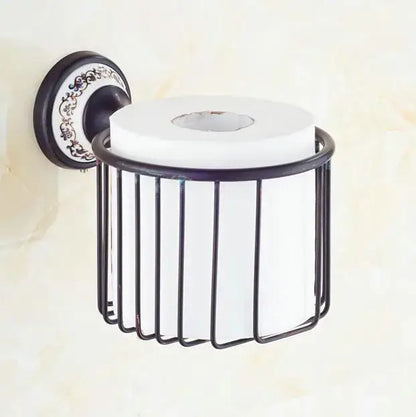 Ornate black wrought iron toilet paper holder with decorative plate and white roll in bathroom accessories set