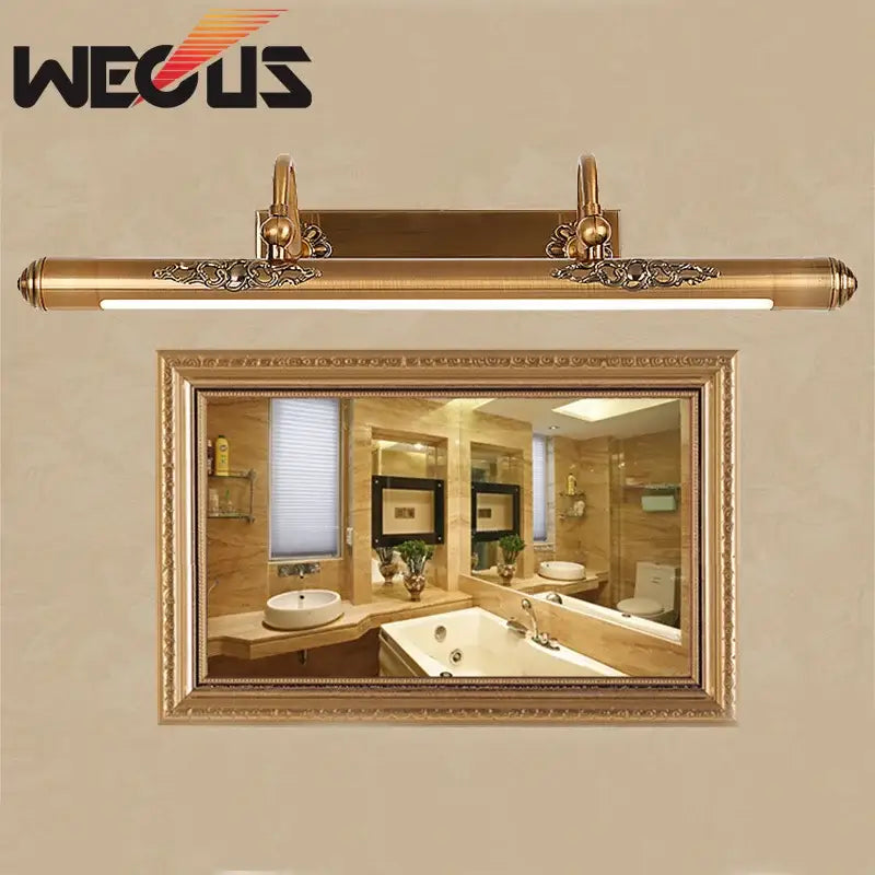 Ornate brass bathroom mirror lamp with gold finish, decorative scrollwork ends, and sleek modern led strip light
