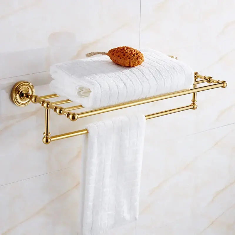 Ornate decorbites brass gold towel rack with two bars holding white towels in brass gold bathroom hardware set
