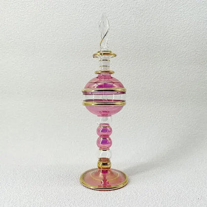 A delicate pink and clear glass bottle jewelry ornament with gold bands and an ornate stopper for bedroom decor