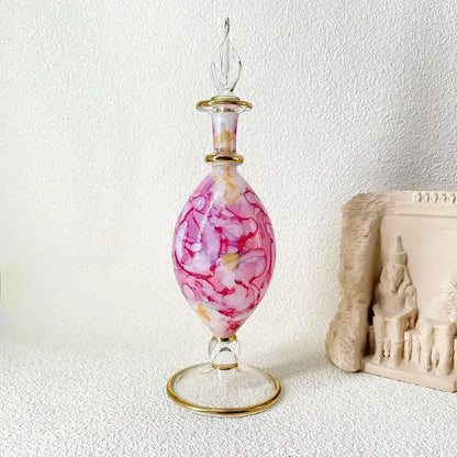 Ornate pink and white marbled glass bottle jewelry ornament with gold accents and elegant footed base for bedroom decor