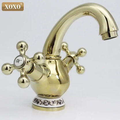 Ornate gold finished brass double handle chrome basin faucet with cross handles and decorative ceramic base for bathroom