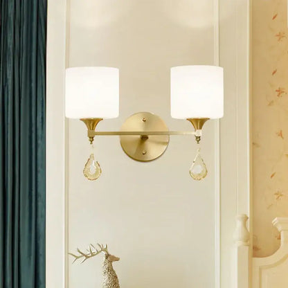 Ornate gold decorbites crystal copper wall lamp with two white glass shades and dangling crystal teardrop accents for bedroom decor