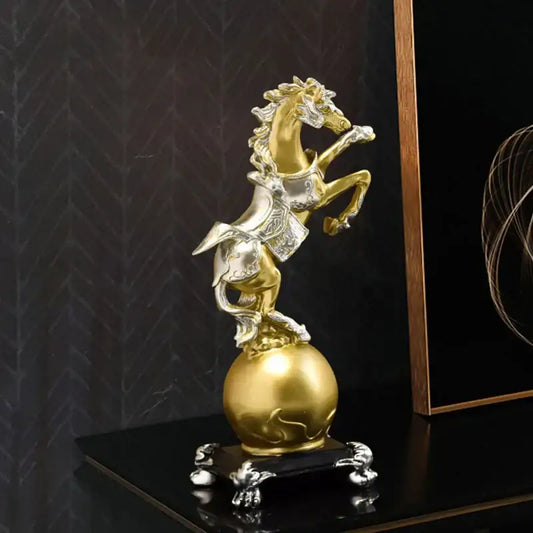 A decorbites golden horse sculpture in gold and silver with intricate detailing on a black ornate base for living room decor