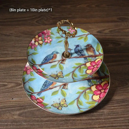 Ornate gold two-tiered fruit plates set with light blue ceramic painted birds and flowers with gold-toned handles