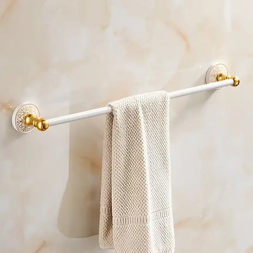 Ornate gold and white floral decorbites bathroom accessories set towel rack with circular mounts holding a beige towel