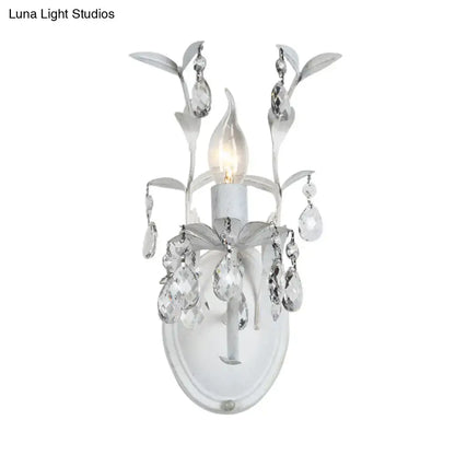 Elegant ornate silver leaf wall light fixture with dangling clear crystals and frosted glass for bedroom sconce lighting