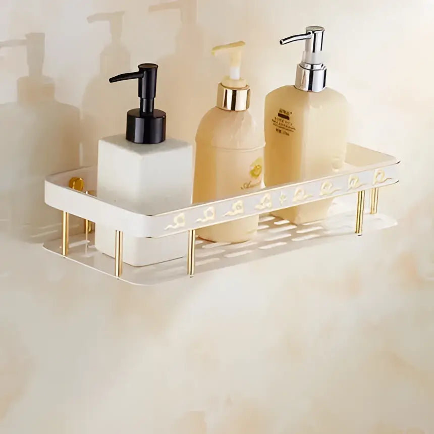 Gold-toned metal bathroom shelf with decorative edge holding soap dispensers from ornate white and gold decorbites bath hardware set
