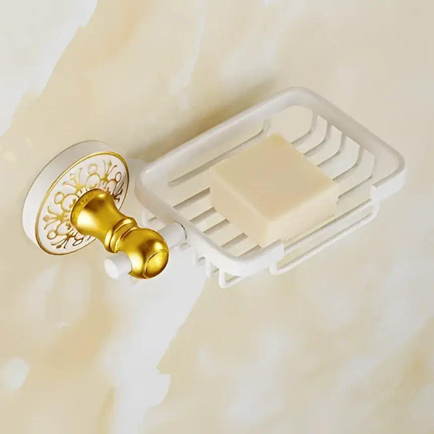 Ornate white wire soap dish with gold-toned wall mount holding pale yellow soap in decorbites bath hardware set