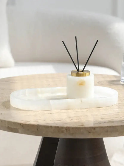 White cylindrical reed diffuser with gold cap and black reeds on oval white decorbites calacatta marble vanity tray
