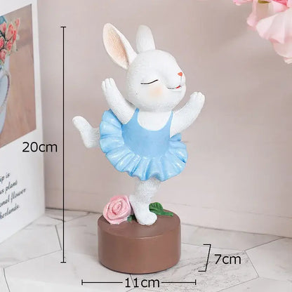 White ceramic ballet rabbit dancer sculpture wearing a light blue tutu on a brown base with a pink rose for bedroom decor