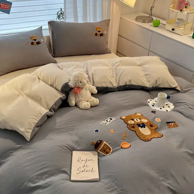 Gray plush teddy bear with pink scarf sits on bed featuring pastel decorbites cartoon embroidered cotton bedding set