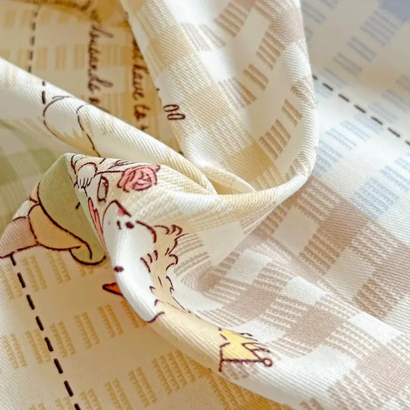 A cream silk scarf with cartoon pattern and handwritten text accompanies pastel checkered cotton grid bedding set decorbites